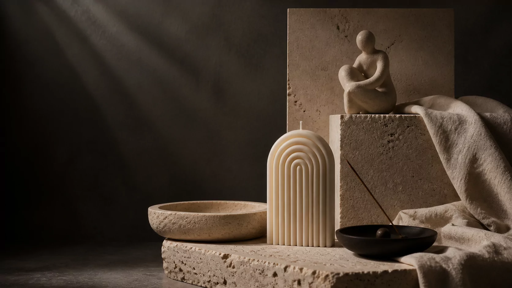 Selección de objetos decorativos sobre piedra y lino con luz cálida